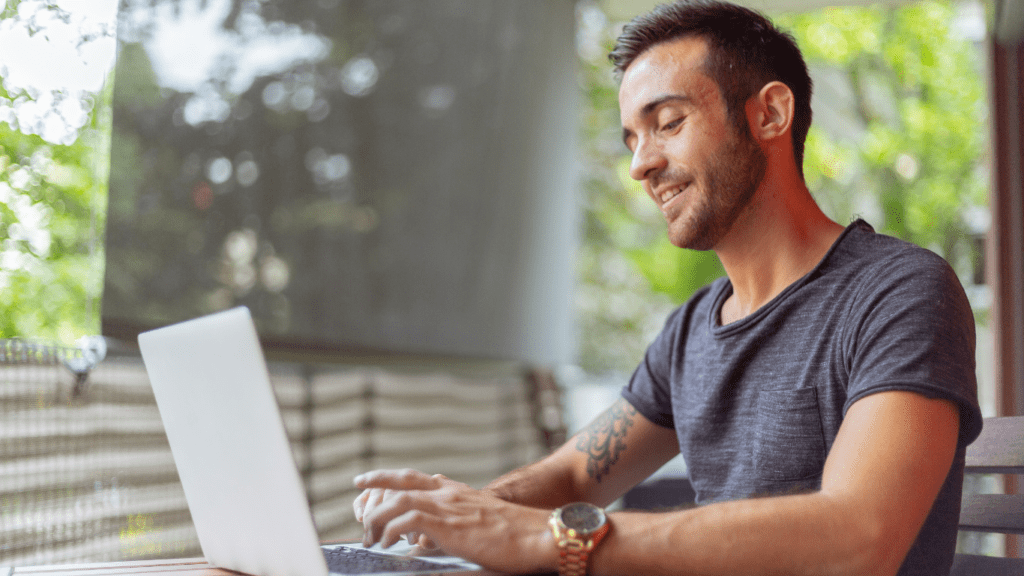 A person smiling while working on a laptop